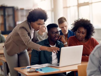 African American professor and her students using laptop during lecture in the classroom.